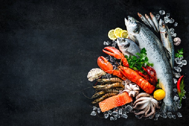 Fresh fish and seafood arrangement on black stone background